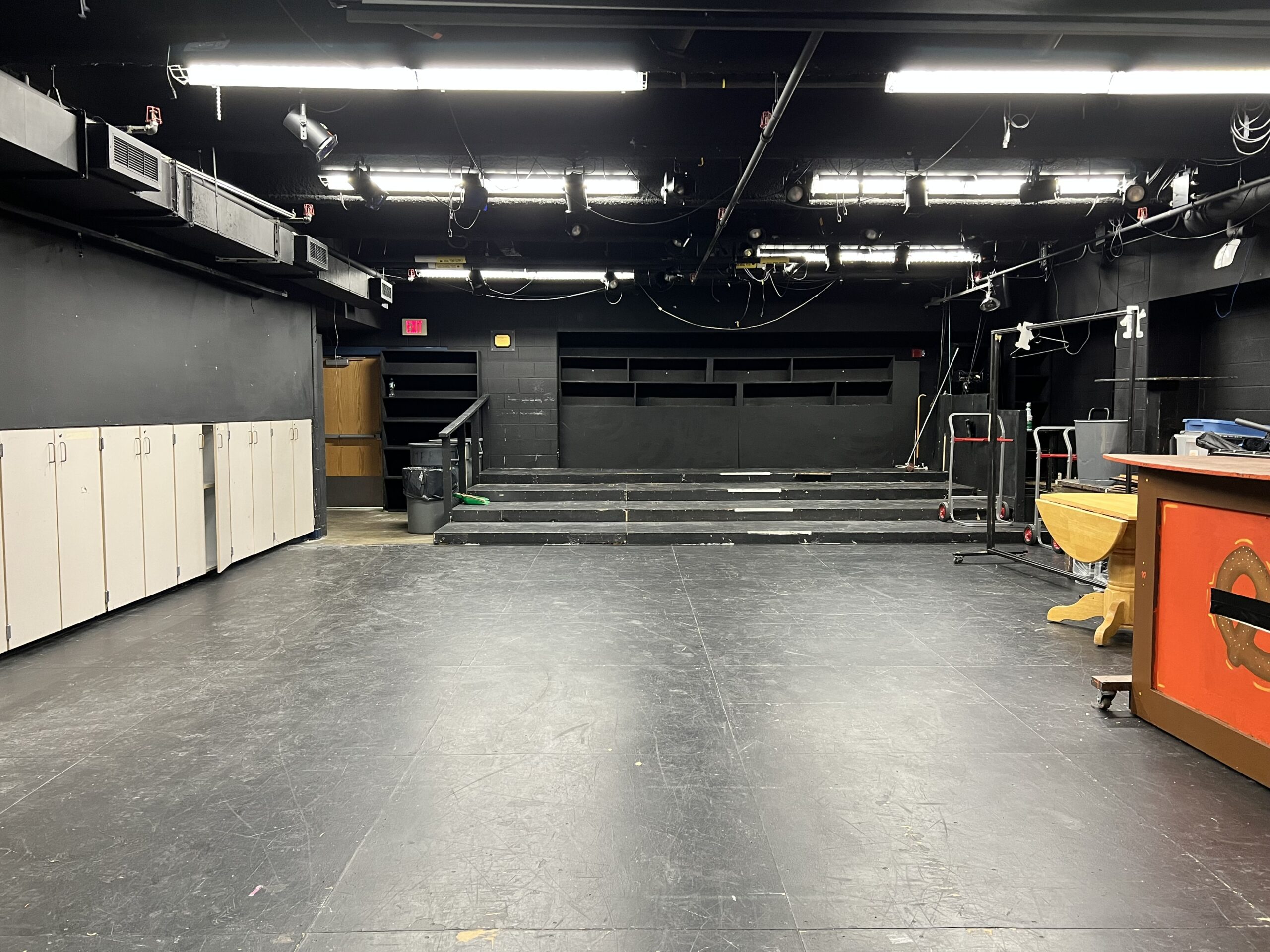 an empty theater space with black floor and bleachers